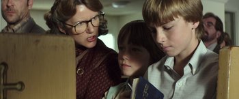 Movie still from “American Sniper” (2014), directed by Clint Eastwood – A woman and two boys are looking at a book; Close Up shot, Low angle