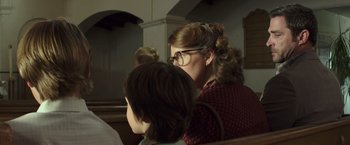 Movie still from “American Sniper” (2014), directed by Clint Eastwood – A woman sitting next to another woman in a church; Close Up shot, Over the shoulder angle