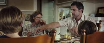 Movie still from “American Sniper” (2014), directed by Clint Eastwood – A man and a woman sitting at a dining table; Medium shot, Low angle