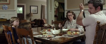 Movie still from “American Sniper” (2014), directed by Clint Eastwood – A woman sitting at a table with a plate of food; Medium shot, Over the shoulder angle