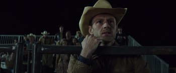 Movie still from “American Sniper” (2014), directed by Clint Eastwood – A man in a cowboy hat is holding a pole; Close Up shot, Low angle