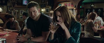 Movie still from “American Sniper” (2014), directed by Clint Eastwood – A man and a woman sitting at a table drinking; Medium shot, Over the shoulder angle