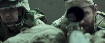 Movie still from “American Sniper” (2014), directed by Clint Eastwood – A person wearing a camouflage suit and a gas mask; Extreme Close Up shot, Over the shoulder angle