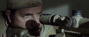 Movie still from “American Sniper” (2014), directed by Clint Eastwood – A person looking through a telescope; Close Up shot, Over the shoulder angle