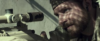 Movie still from “American Sniper” (2014), directed by Clint Eastwood – A person holding a rifle; Close Up shot, Over the shoulder angle