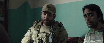 Movie still from “American Sniper” (2014), directed by Clint Eastwood – A man in a military uniform and a hat; Close Up shot, Over the shoulder angle