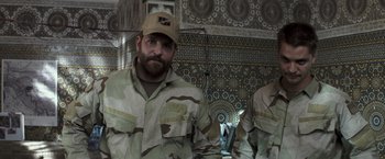 Movie still from “American Sniper” (2014), directed by Clint Eastwood – A man with a beard wearing a military uniform; Medium shot, Over the shoulder angle