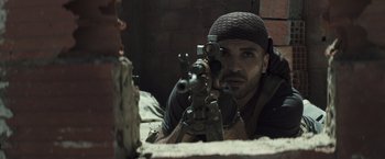 Movie still from “American Sniper” (2014), directed by Clint Eastwood – A man with a rifle aiming at a brick wall; Close Up shot, Low angle