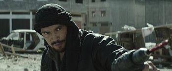 Movie still from “American Sniper” (2014), directed by Clint Eastwood – A man in a black jacket and a black hat; Close Up shot, Over the shoulder angle