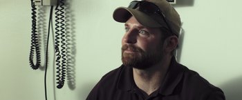Movie still from “American Sniper” (2014), directed by Clint Eastwood – A man with a beard wearing a hat and sunglasses; Close Up shot, High angle