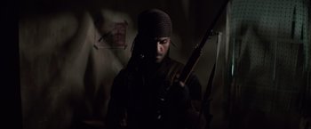 Movie still from “American Sniper” (2014), directed by Clint Eastwood – A man holding a rifle in a dark room; Close Up shot, Low angle