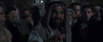 Movie still from “American Sniper” (2014), directed by Clint Eastwood – A group of men in black and white clothing; Medium shot, Over the shoulder angle