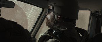 Movie still from “American Sniper” (2014), directed by Clint Eastwood – A man with a goatee wearing sunglasses and a jacket; Close Up shot, Over the shoulder angle