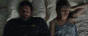 Movie still from “American Sniper” (2014), directed by Clint Eastwood – A man and a woman laying in a bed together; Medium shot, Overhead angle