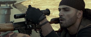 Movie still from “American Sniper” (2014), directed by Clint Eastwood – A man holding a rifle and looking through a scope; Close Up shot, Low angle