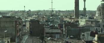Movie still from “American Sniper” (2014), directed by Clint Eastwood – An aerial view of a large city with a lot of buildings; Extreme Wide shot, High angle