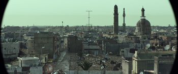 Movie still from “American Sniper” (2014), directed by Clint Eastwood – An aerial view of an urban area with a clock tower in the background; Extreme Wide shot, High angle