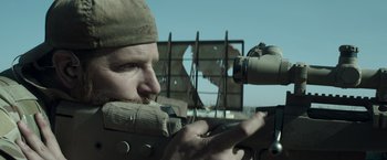 Movie still from “American Sniper” (2014), directed by Clint Eastwood – A man with a rifle looking through a telescope; Close Up shot, Over the shoulder angle