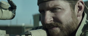 Movie still from “American Sniper” (2014), directed by Clint Eastwood – A man with a beard and mustache; Close Up shot, Over the shoulder angle