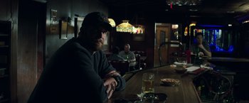 Movie still from “American Sniper” (2014), directed by Clint Eastwood – A man sitting at a table in a restaurant; Medium shot, Over the shoulder angle