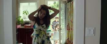 Movie still from “American Sniper” (2014), directed by Clint Eastwood – A woman standing in front of a man holding a guitar; Medium shot, Over the shoulder angle