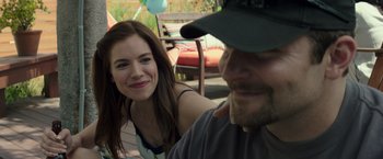 Movie still from “American Sniper” (2014), directed by Clint Eastwood – A man and a woman sitting next to each other on a deck; Close Up shot, Over the shoulder angle
