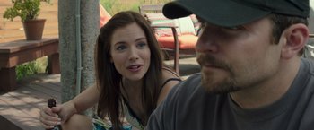 Movie still from “American Sniper” (2014), directed by Clint Eastwood – A woman sitting next to a man in a baseball cap; Close Up shot, Over the shoulder angle