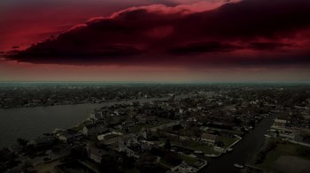 Movie still from “Amityville Uprising” (2022), directed by Thomas J. Churchill – An aerial view of a city with a red sky in the background; Extreme Wide shot, High angle