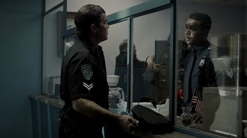 Movie still from “Amityville Uprising” (2022), directed by Thomas J. Churchill – A police officer holding a hat in front of a mirror; Medium shot, Over the shoulder angle