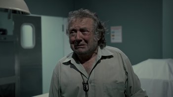 Movie still from “Amityville Uprising” (2022), directed by Thomas J. Churchill – An older man in a white shirt is standing in a room; Close Up shot, Over the shoulder angle