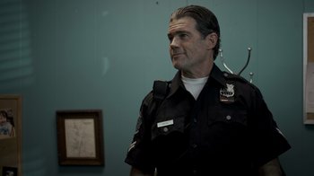 Movie still from “Amityville Uprising” (2022), directed by Thomas J. Churchill – A man in a police uniform looking to his left; Medium shot, Low angle