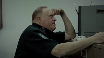 Movie still from “Amityville Uprising” (2022), directed by Thomas J. Churchill – A man sitting in front of a computer monitor; Close Up shot, Over the shoulder angle