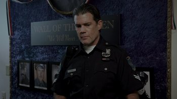 Movie still from “Amityville Uprising” (2022), directed by Thomas J. Churchill – A man in a police uniform standing in front of a wall; Close Up shot, Low angle