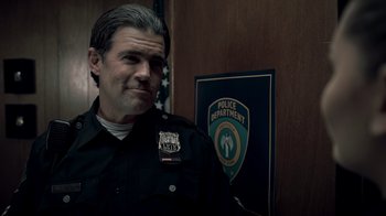 Movie still from “Amityville Uprising” (2022), directed by Thomas J. Churchill – A man in a police uniform standing in front of a police department sign; Close Up shot, Over the shoulder angle