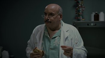 Movie still from “Amityville Uprising” (2022), directed by Thomas J. Churchill – A man in a lab coat holding a hot dog; Medium shot, Low angle