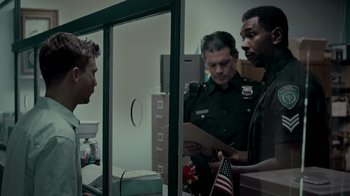 Movie still from “Amityville Uprising” (2022), directed by Thomas J. Churchill – A group of men standing next to each other in a room; Medium shot, Over the shoulder angle