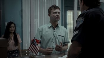 Movie still from “Amityville Uprising” (2022), directed by Thomas J. Churchill – A man standing in front of a mirror talking to a police officer; Medium shot, Over the shoulder angle