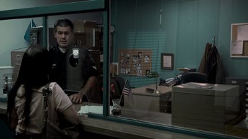 Movie still from “Amityville Uprising” (2022), directed by Thomas J. Churchill – A man sitting in front of a window in an office; Medium shot, Over the shoulder angle