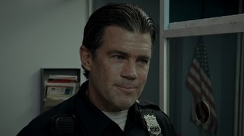Movie still from “Amityville Uprising” (2022), directed by Thomas J. Churchill – A man in a police uniform is smiling for the camera; Close Up shot, Low angle