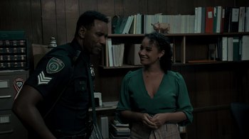 Movie still from “Amityville Uprising” (2022), directed by Thomas J. Churchill – A man and a woman talking to each other in front of a book shelf; Medium shot, Over the shoulder angle