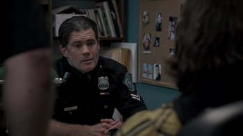 Movie still from “Amityville Uprising” (2022), directed by Thomas J. Churchill – A police officer talking to a woman in a room; Close Up shot, Over the shoulder angle