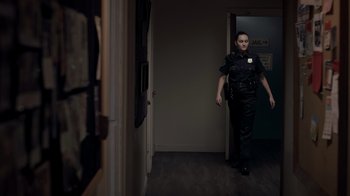 Movie still from “Amityville Uprising” (2022), directed by Thomas J. Churchill – A police officer is walking through a hallway; Medium shot, Over the shoulder angle