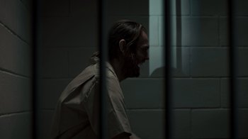 Movie still from “Amityville Uprising” (2022), directed by Thomas J. Churchill – A man in a jail cell looking out of the window; Medium shot, Over the shoulder angle