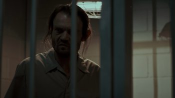 Movie still from “Amityville Uprising” (2022), directed by Thomas J. Churchill – A man with long hair is standing in a jail cell; Close Up shot, Low angle