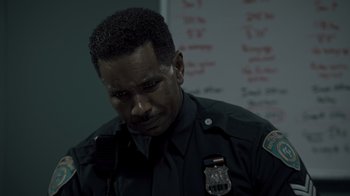 Movie still from “Amityville Uprising” (2022), directed by Thomas J. Churchill – A man in a police uniform is looking down; Close Up shot, Over the shoulder angle