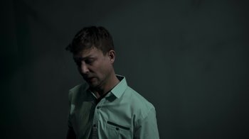 Movie still from “Amityville Uprising” (2022), directed by Thomas J. Churchill – A man in a white shirt is looking down at his face; Close Up shot, Low angle