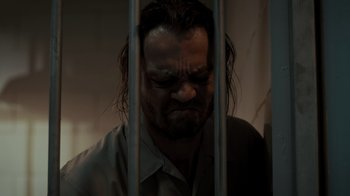 Movie still from “Amityville Uprising” (2022), directed by Thomas J. Churchill – A man with long hair is in a jail cell; Close Up shot, Low angle