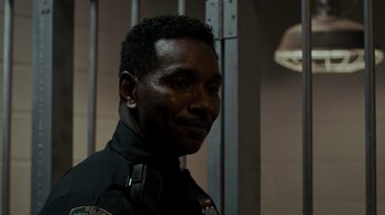 Movie still from “Amityville Uprising” (2022), directed by Thomas J. Churchill – A police officer is smiling for the camera; Close Up shot, Over the shoulder angle