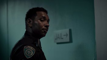 Movie still from “Amityville Uprising” (2022), directed by Thomas J. Churchill – A police officer standing in front of a jail sign; Close Up shot, Over the shoulder angle
