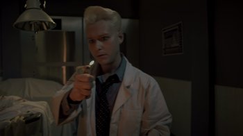 Movie still from “Amityville Uprising” (2022), directed by Thomas J. Churchill – A man in a white lab coat holding a cell phone; Medium shot, Low angle